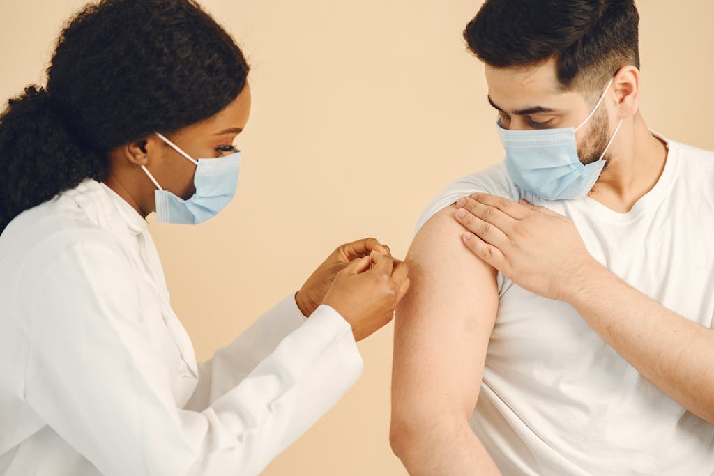 A healthcare worker giving a COVID-19 vaccine to a patient wearing a face mask.