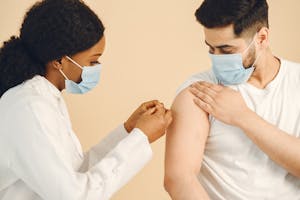 A healthcare worker giving a COVID-19 vaccine to a patient wearing a face mask.